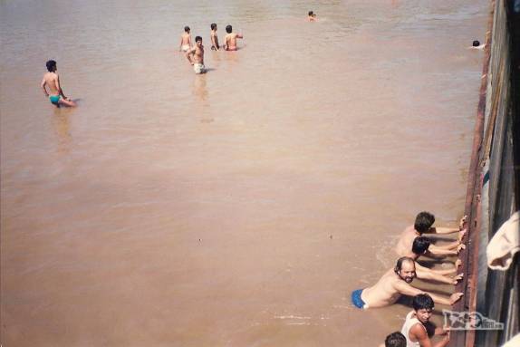 Passageiros fazem força para tentar desatolar nosso barco do leito do rio Amazonas, na região de Iquitos, no Peru (foto de Julho de 1990)